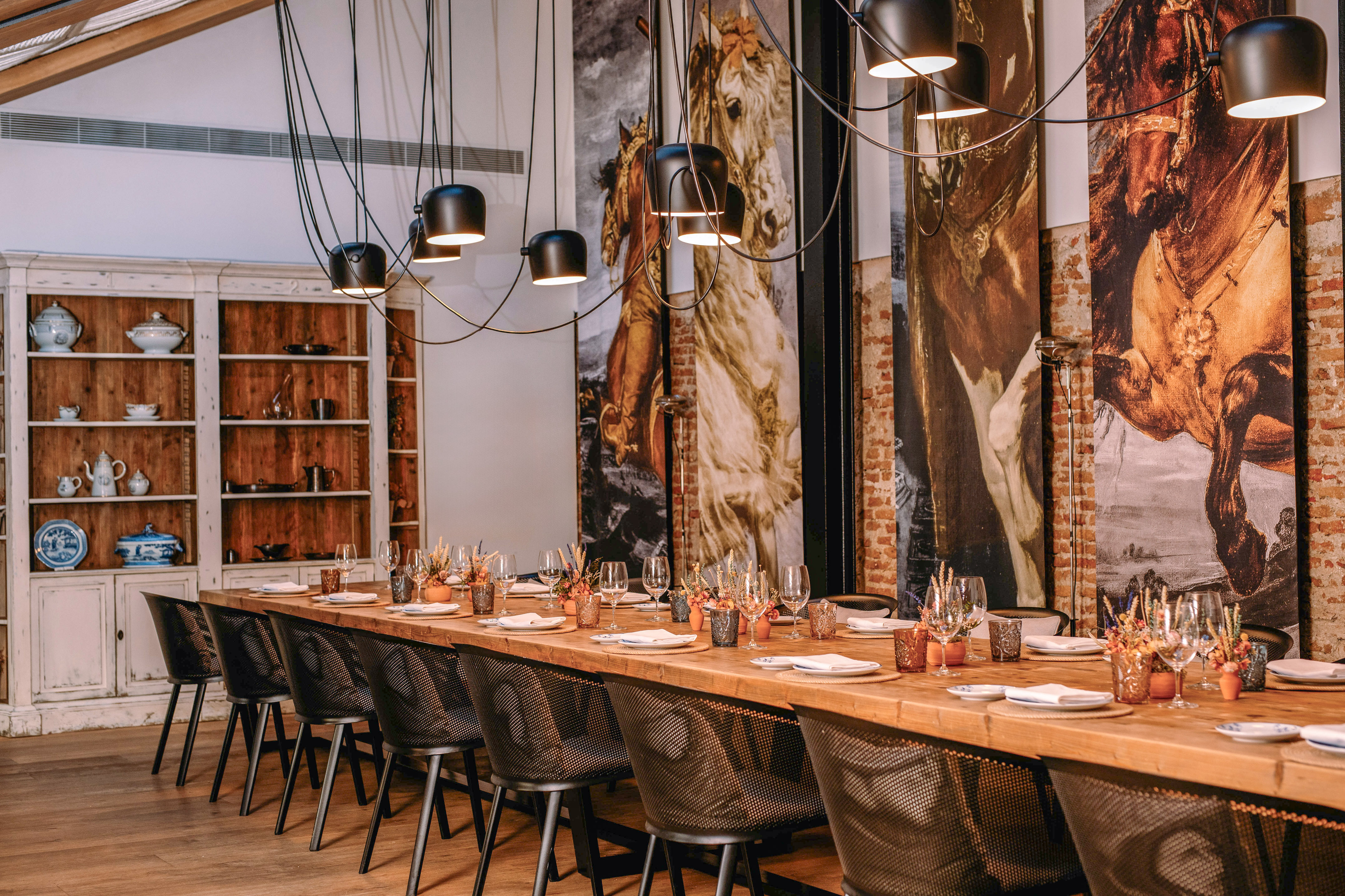 Rustic-modern dining room with large horse murals, long table, and pendant lighting.