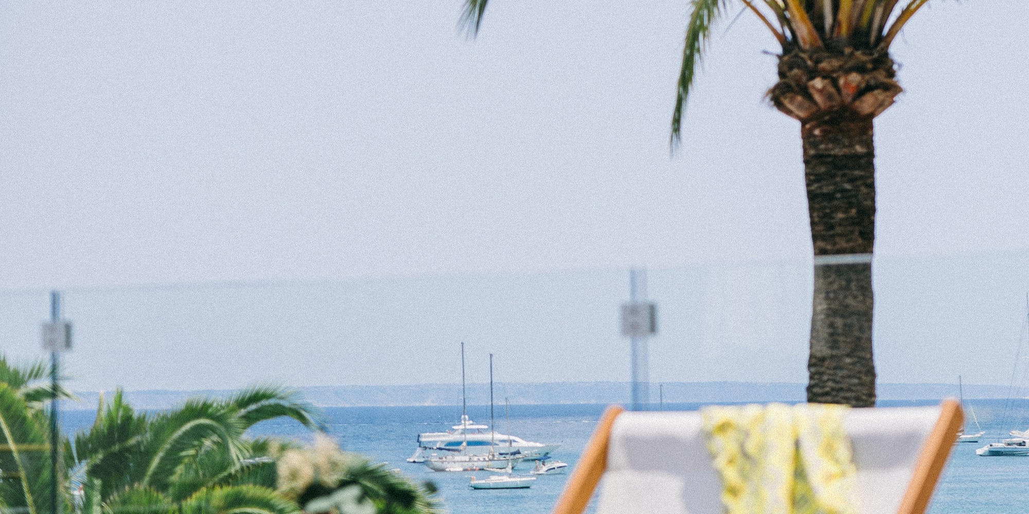 a chair and table with palm trees and water in the background