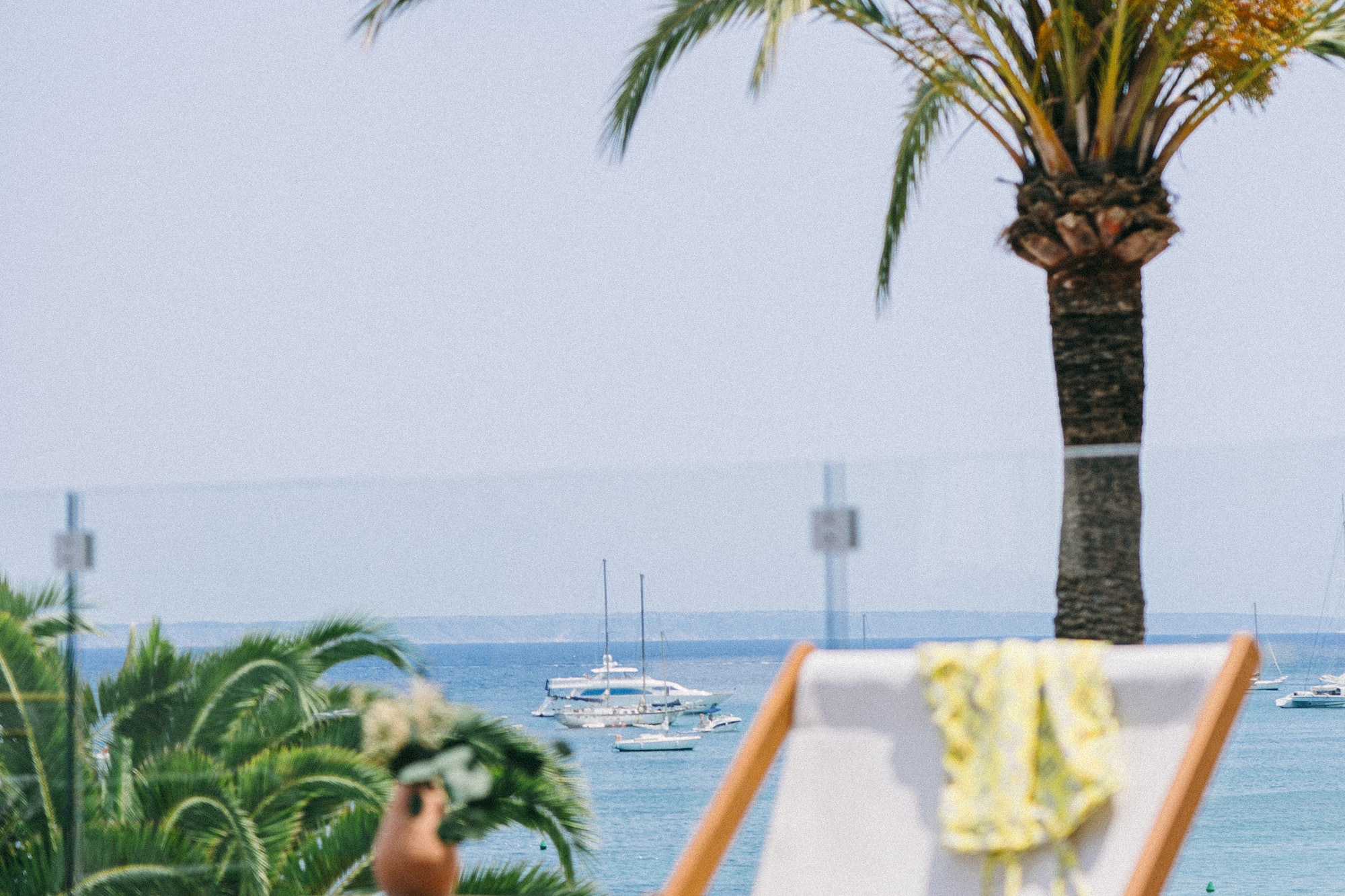 a chair and table with palm trees and water in the background