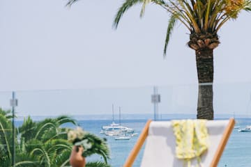 a chair and table with palm trees and water in the background
