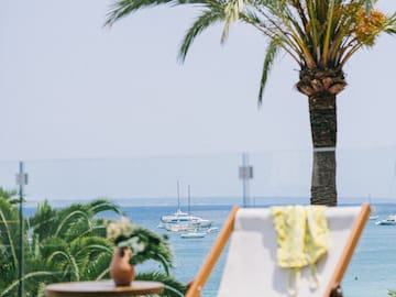 a chair and table with palm trees and water in the background