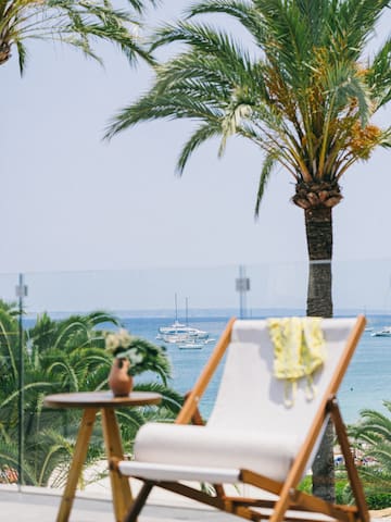 a chair and table with palm trees and water in the background