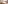 Modern hotel bedroom with ocean view, white bed, and wood accents.
