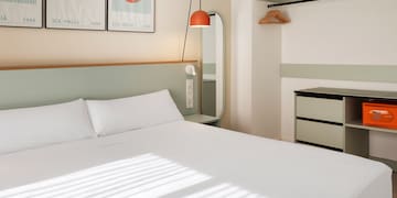 a bed with white sheets and a mirror