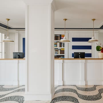 a white and black patterned floor with a white column and a white counter