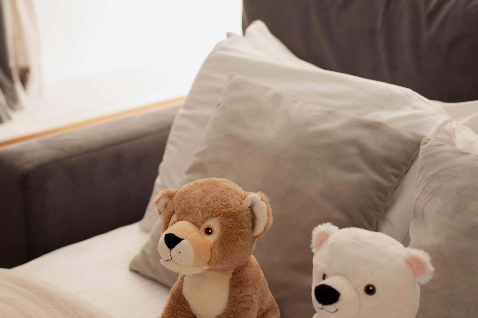 Brown lion and white polar bear plush toys on a cozy bed.