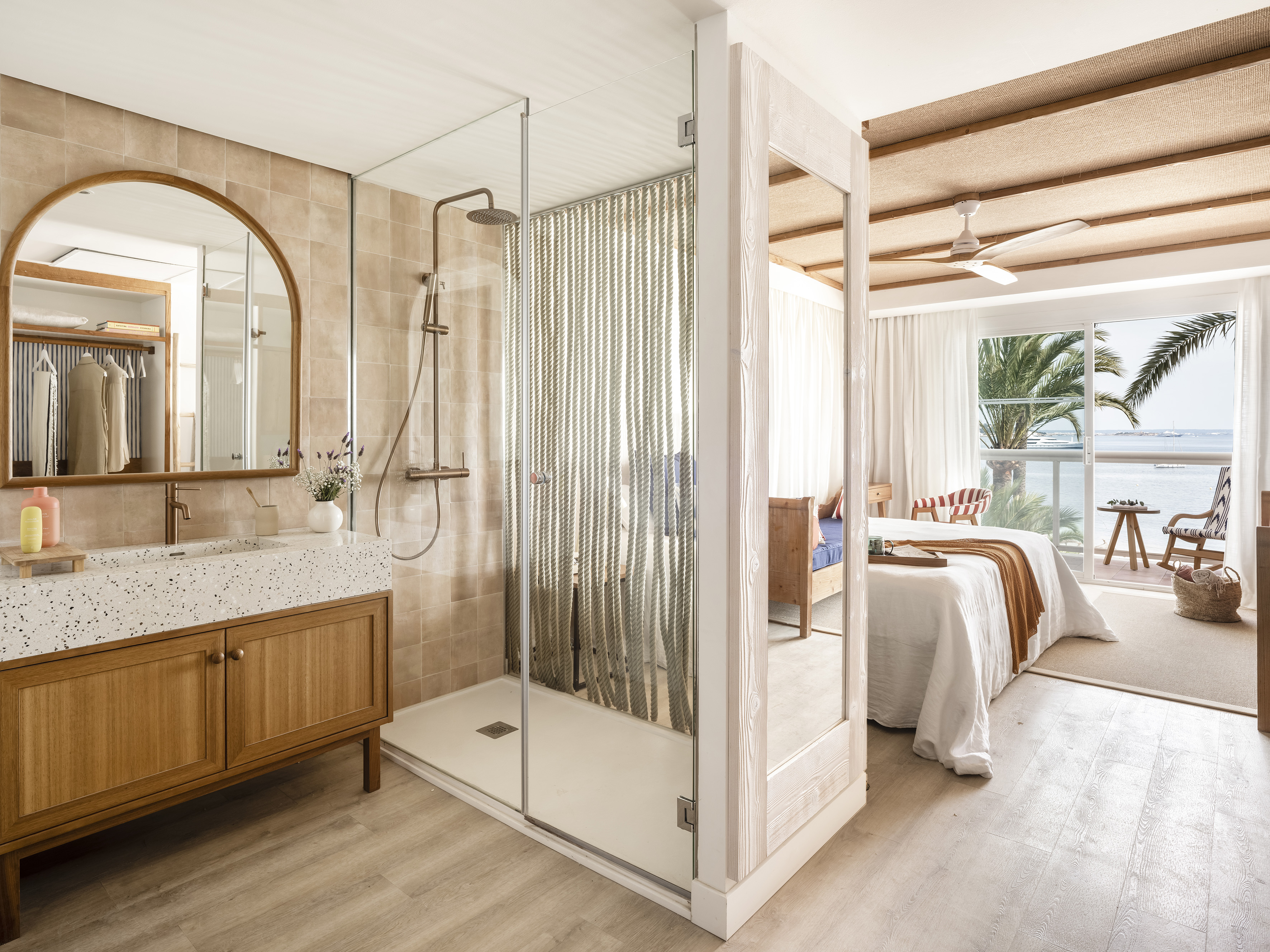 Hotel suite with modern open-concept bathroom, bedroom, and ocean view.