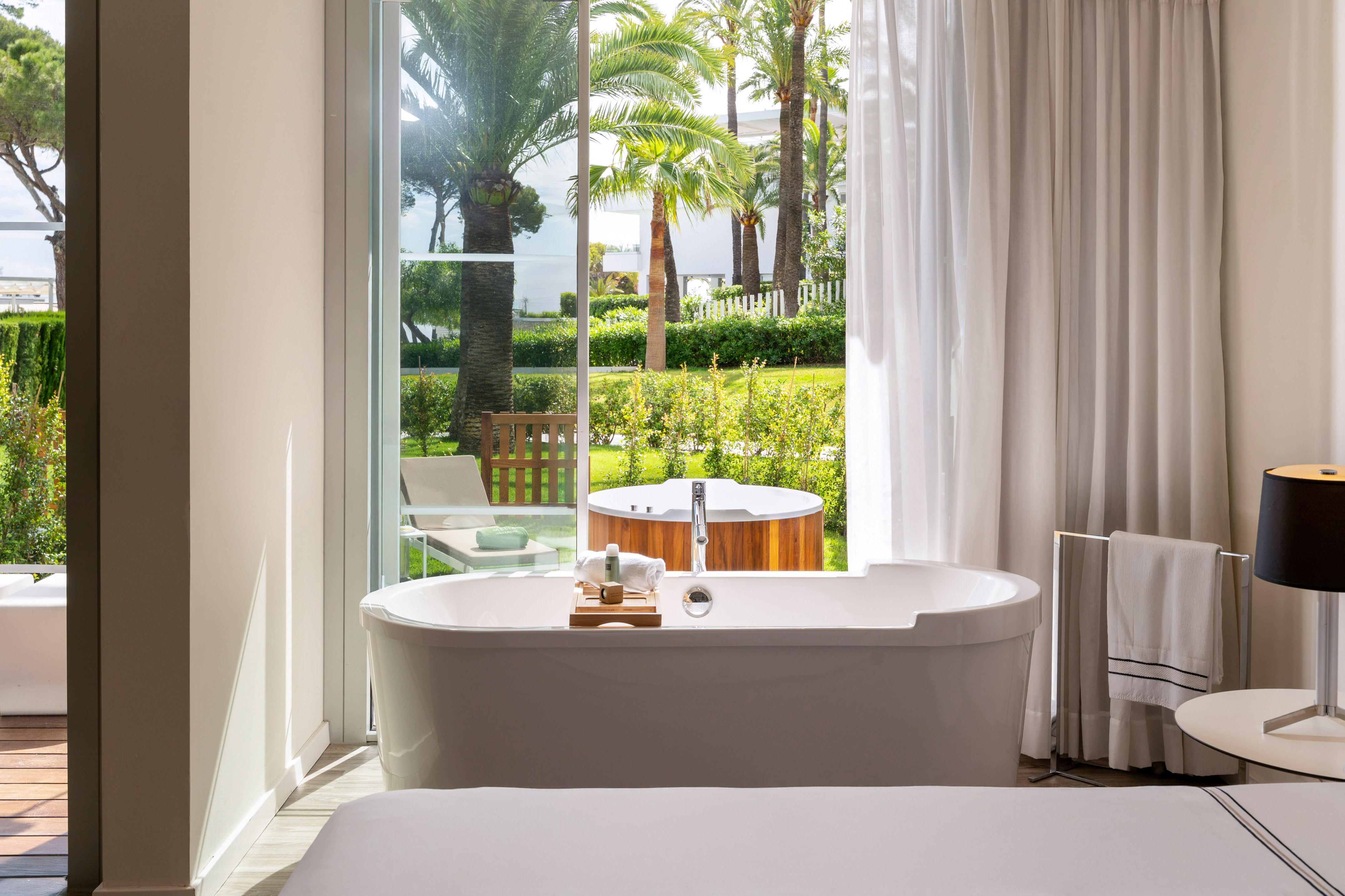 Luxury hotel room with bathtub facing private garden and outdoor hot tub.