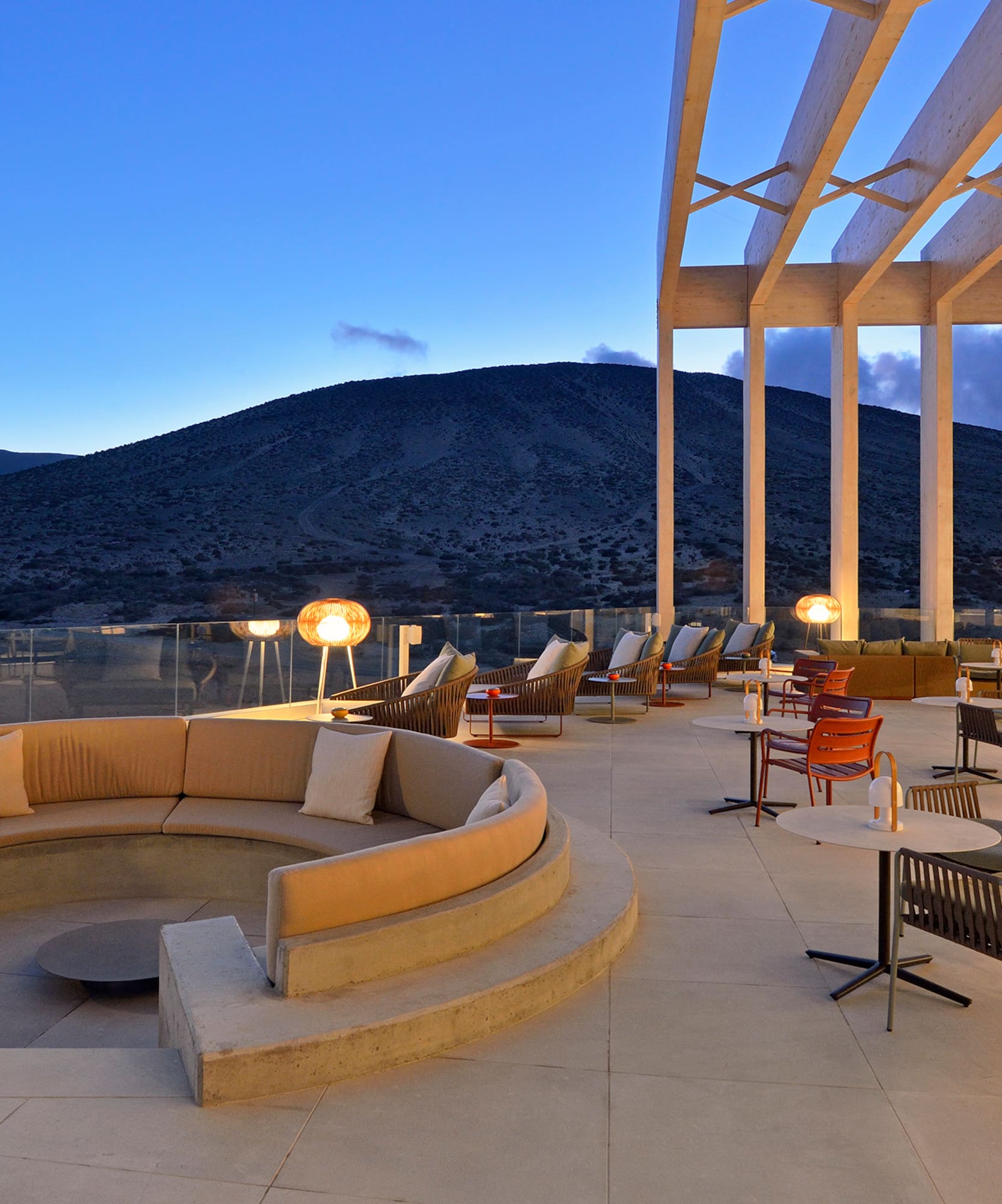 Modern outdoor lounge patio, mountain view at twilight, resort terrace.