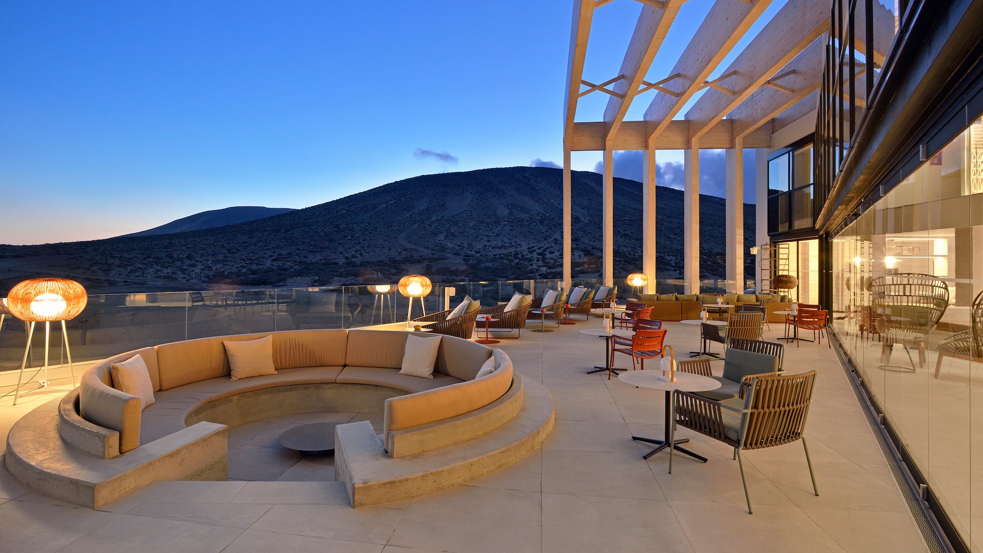 Stylish outdoor lounge terrace, mountain view at dusk, modern seating.