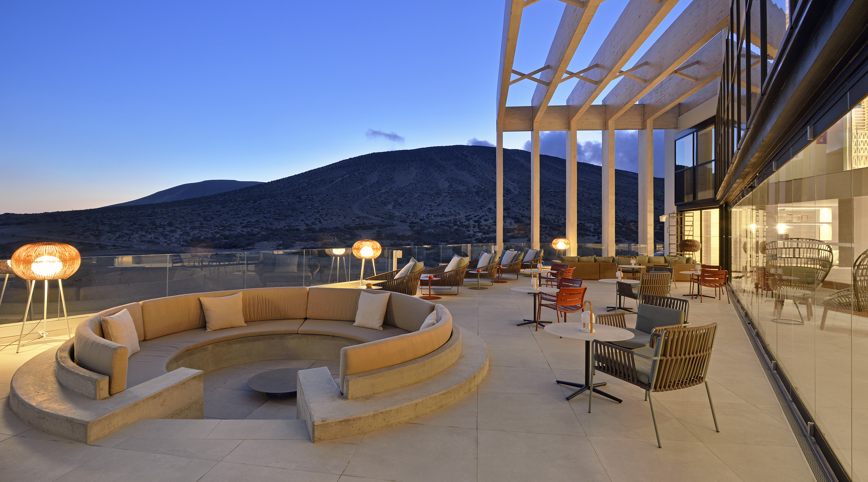 Stylish outdoor lounge terrace, mountain view at dusk, modern seating.
