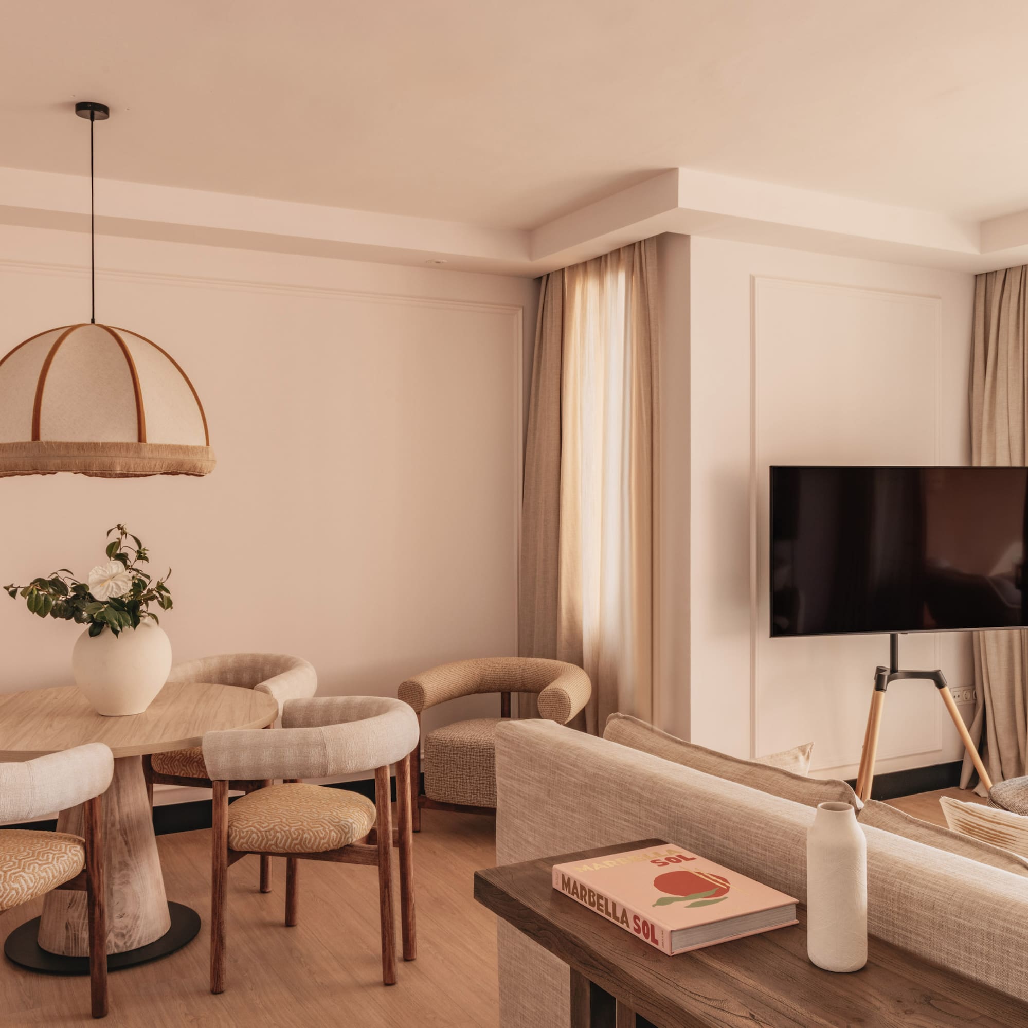 Modern hotel suite living room, dining area, TV, and balcony with sea view.