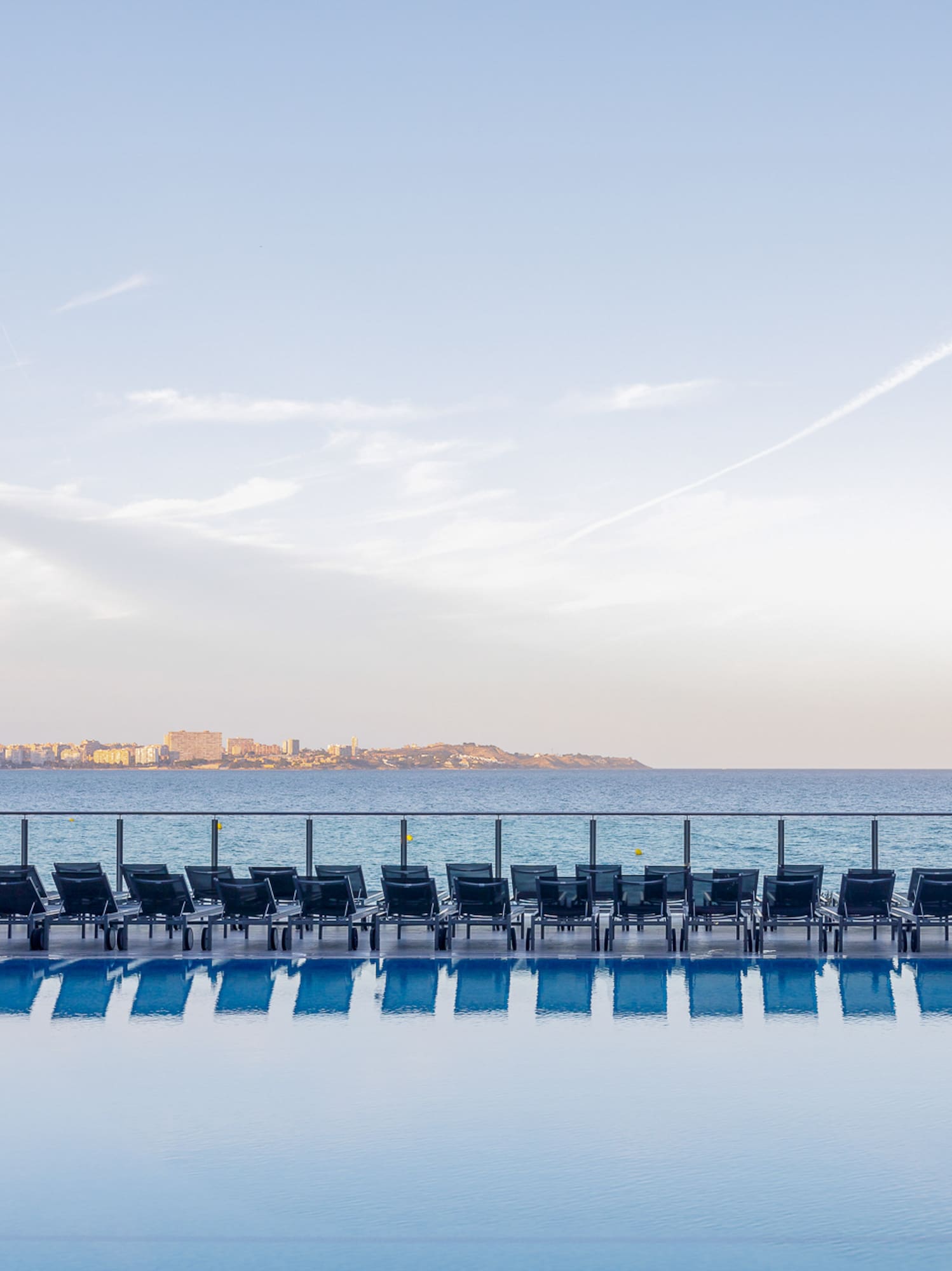 a pool with chairs and a body of water
