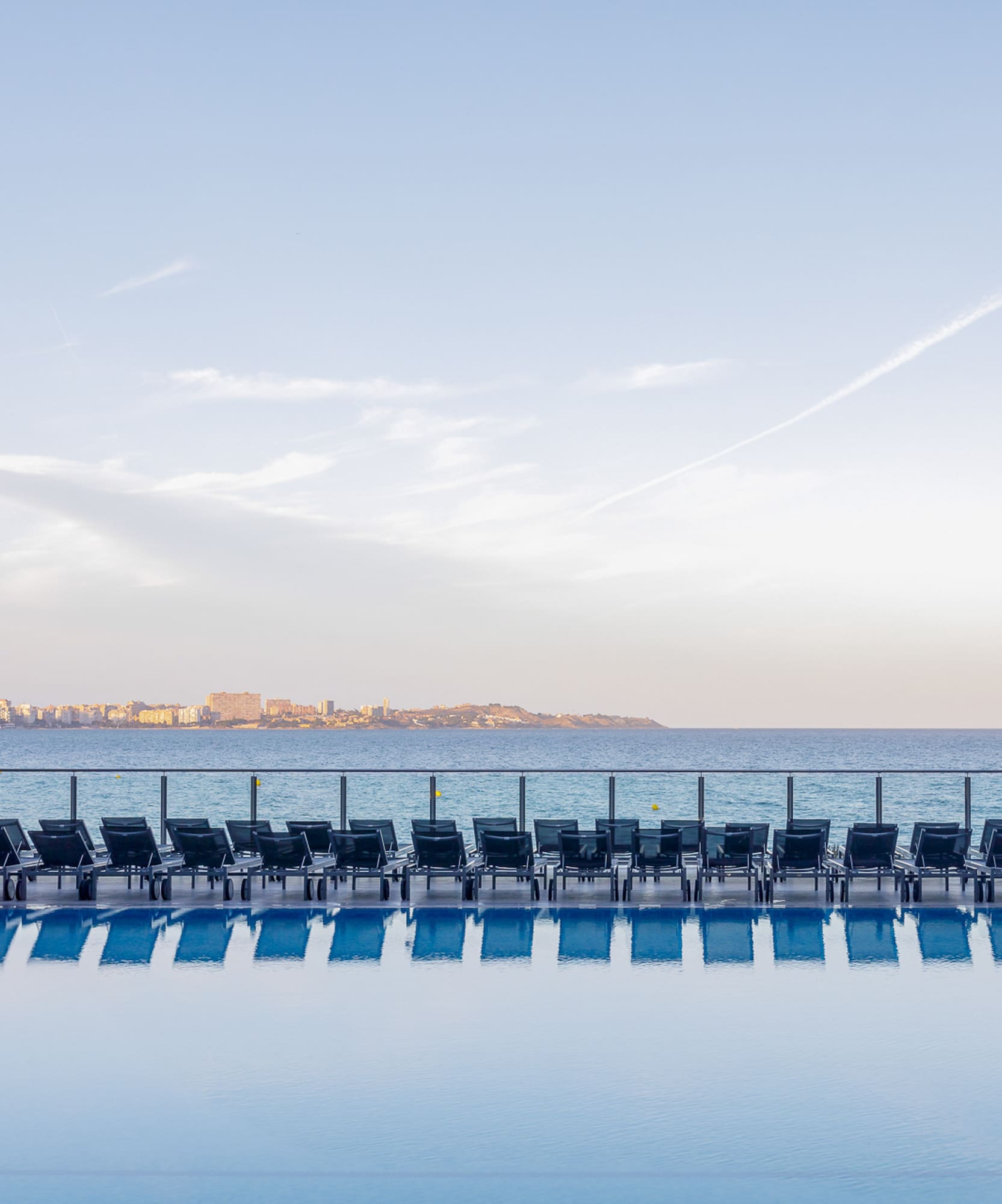 a pool with chairs and a body of water