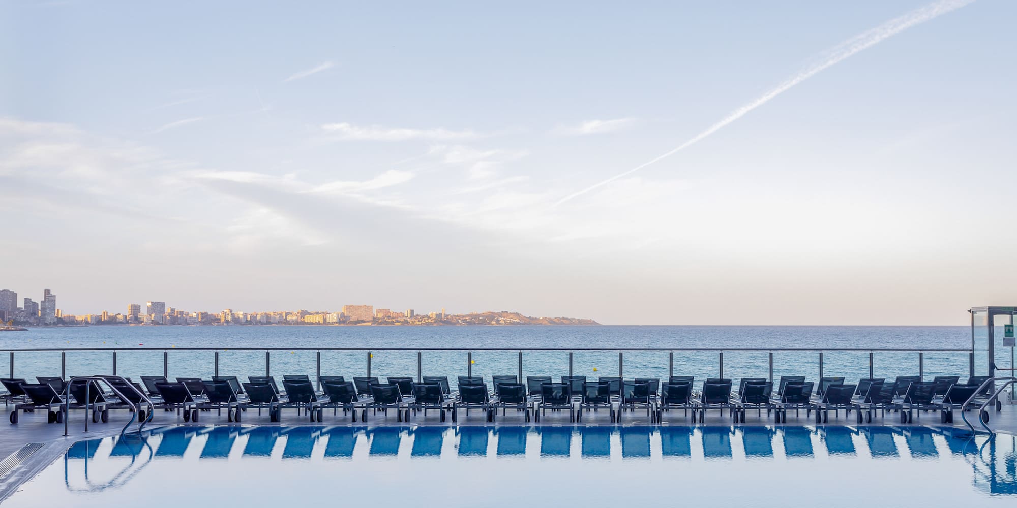 a pool with chairs and a body of water