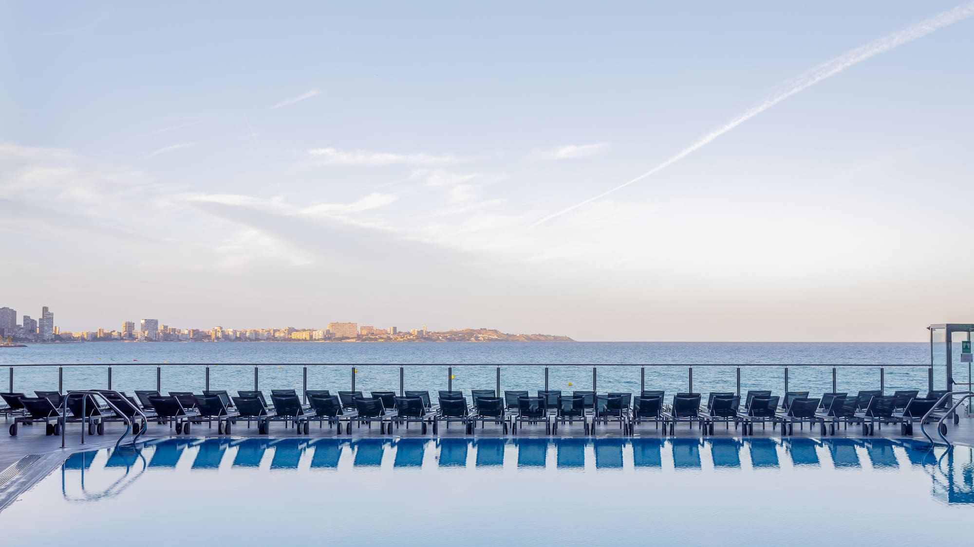 a pool with chairs and a body of water
