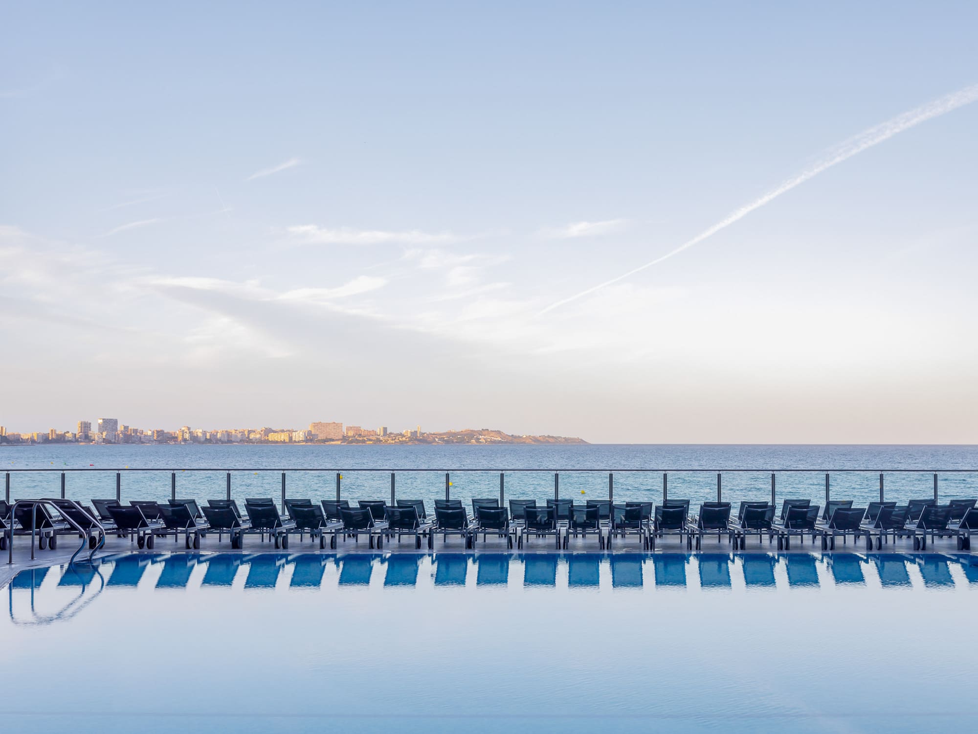 a pool with chairs and a body of water