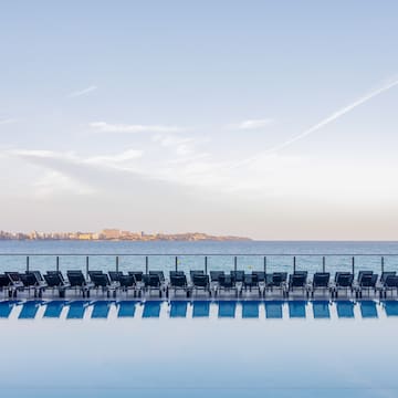 a pool with chairs and a body of water