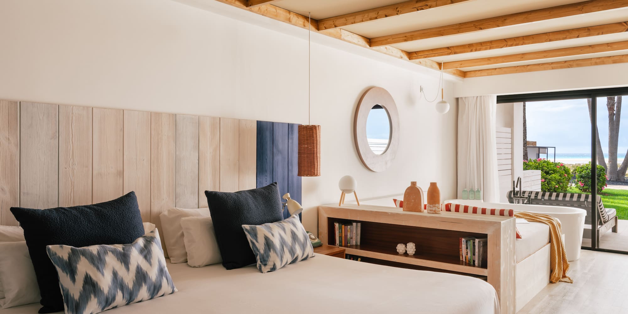 Habitación de hotel con cama, cabecero de madera y vista al mar.