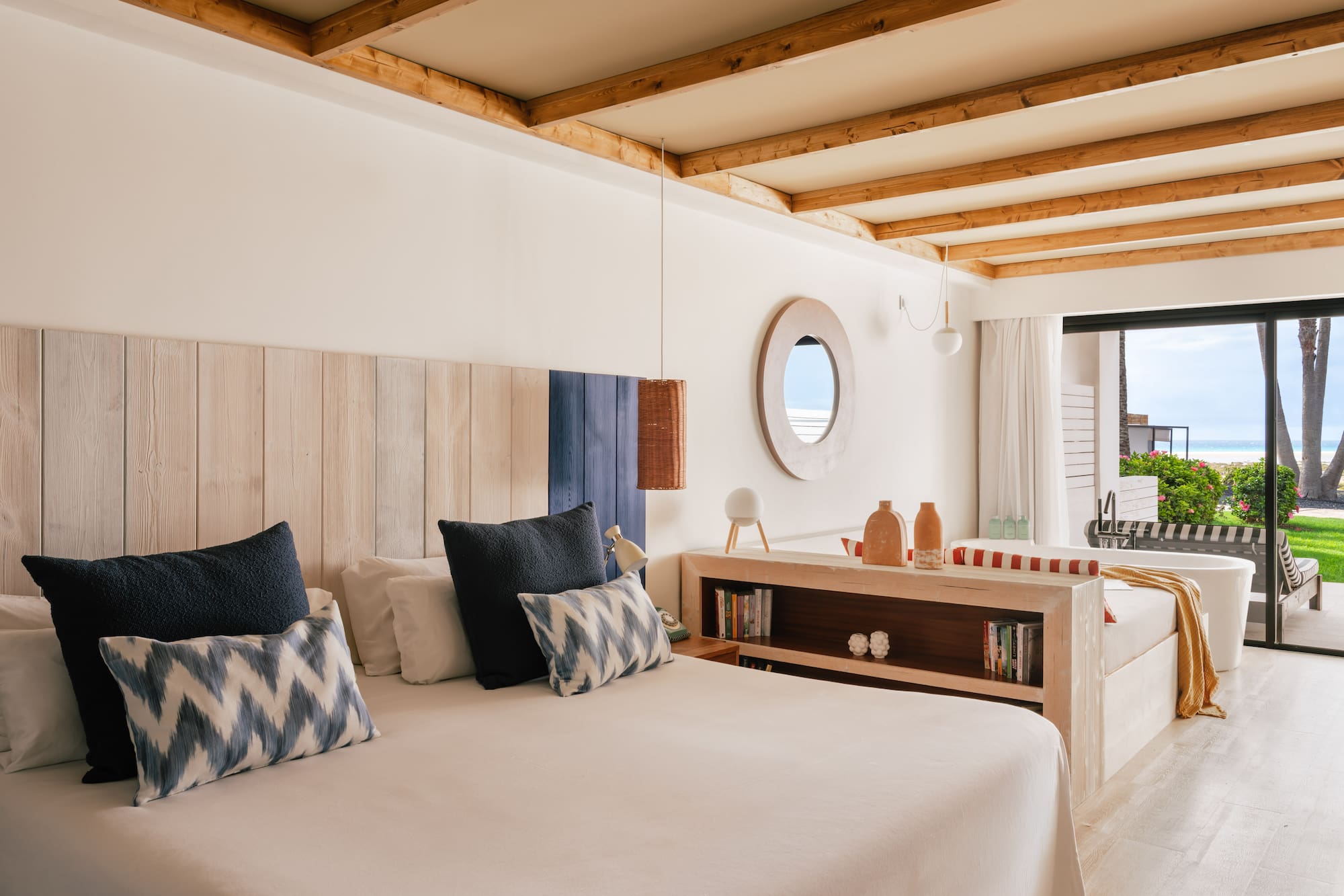 Habitación de hotel con cama, cabecero de madera y vista al mar.