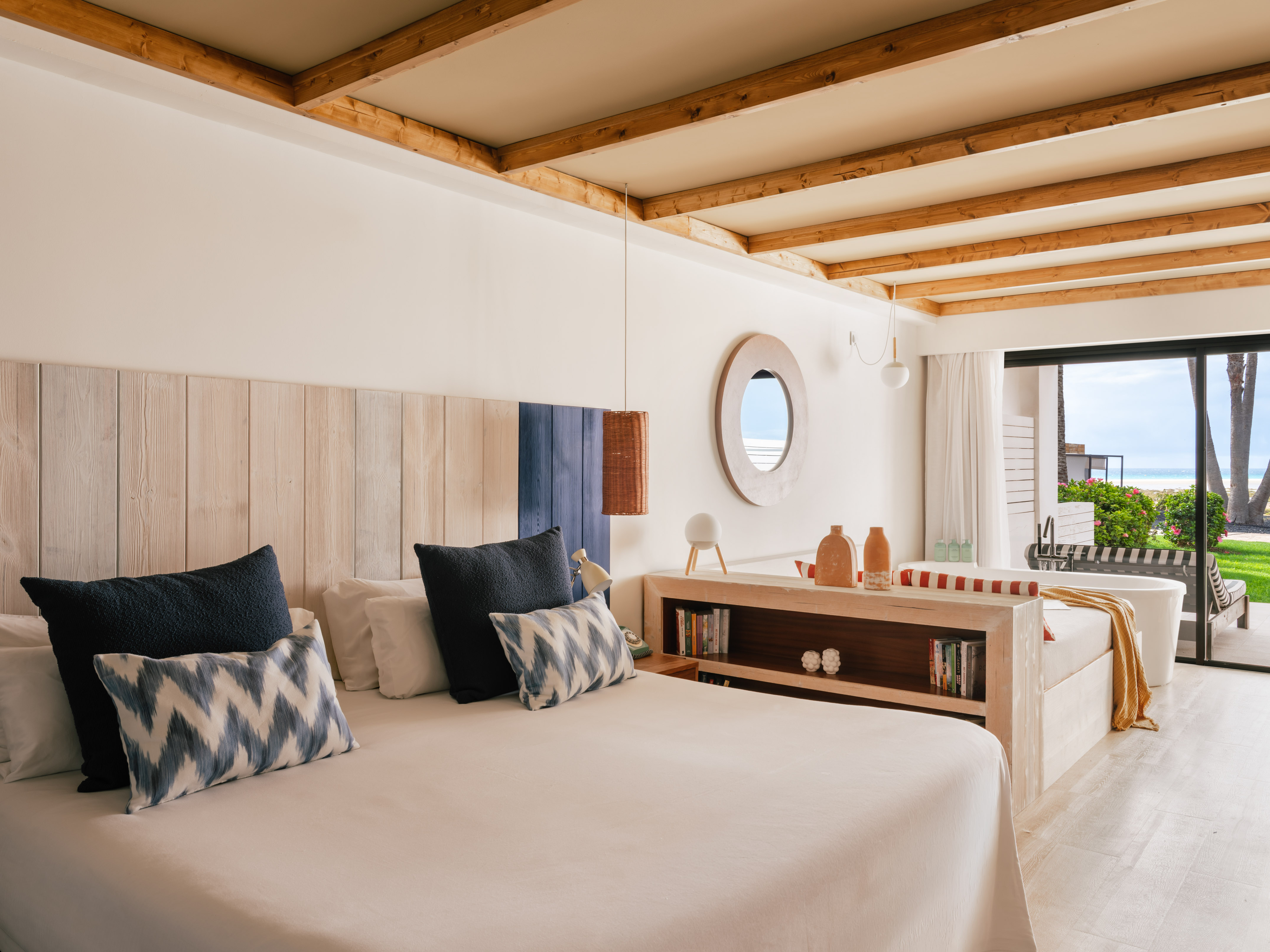 Habitación de hotel con cama, cabecero de madera y vista al mar.