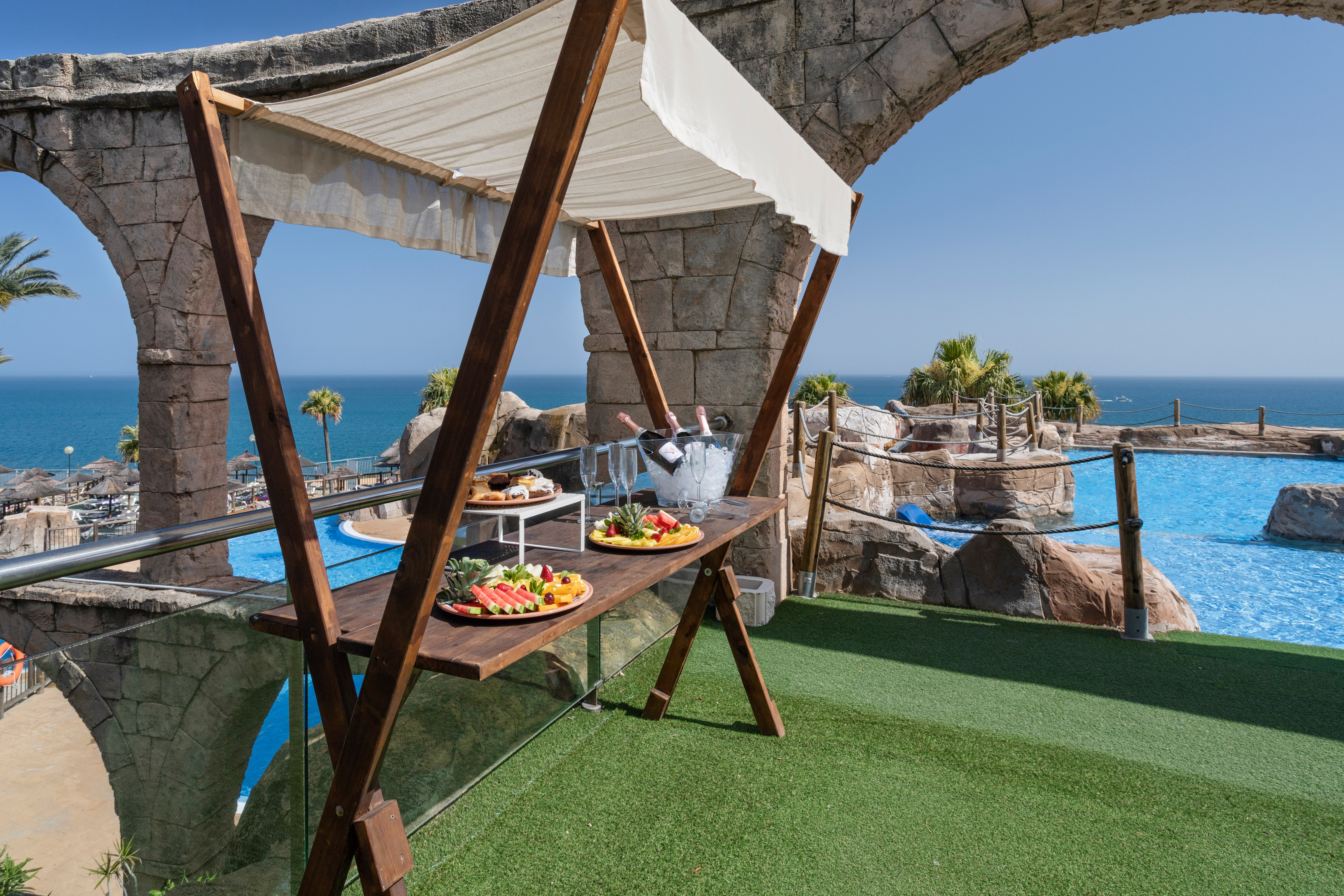 Luxury resort poolside bar with champagne, fruit, pastries, ocean view.