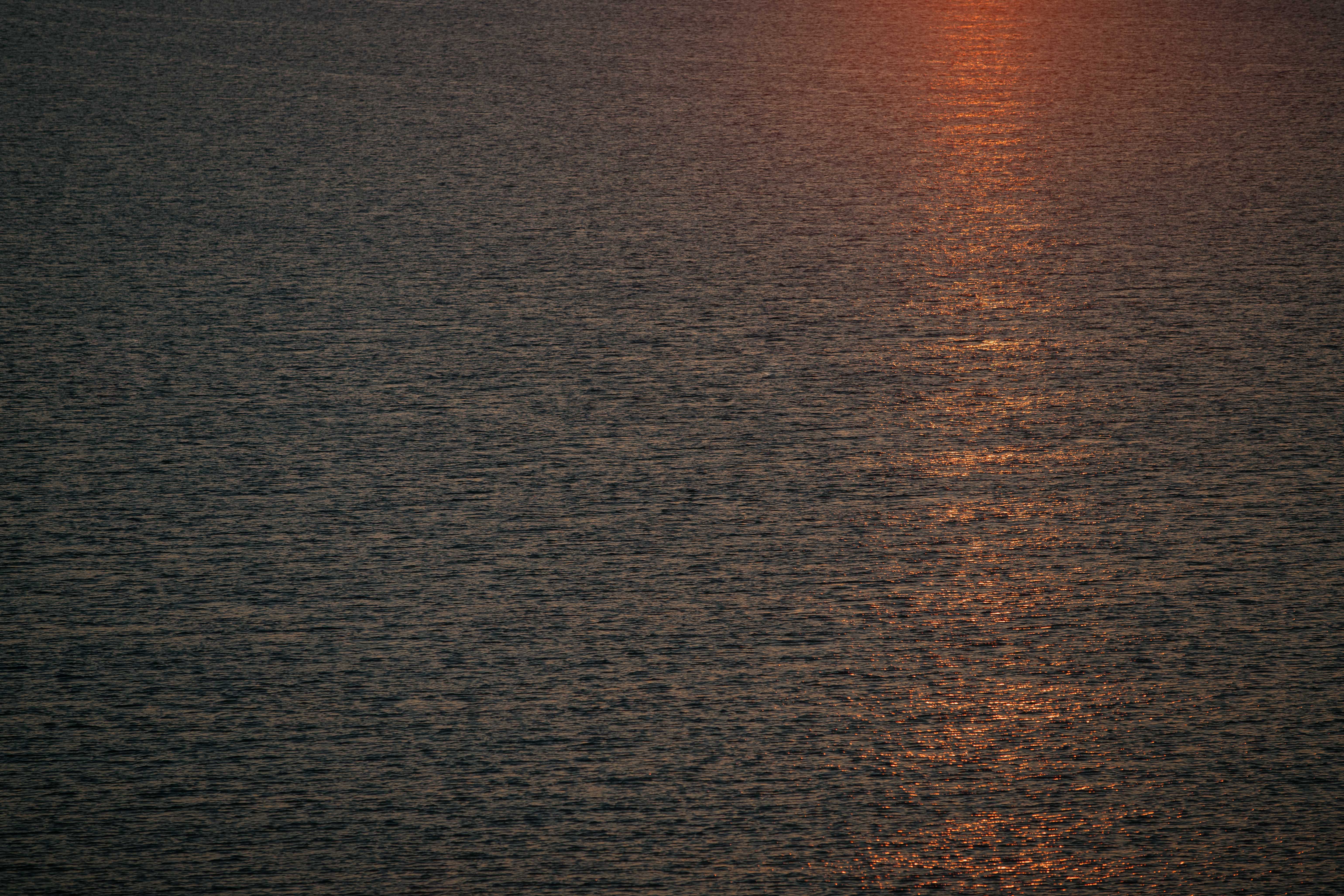 Ondas de agua oscura con reflejo naranja del atardecer.