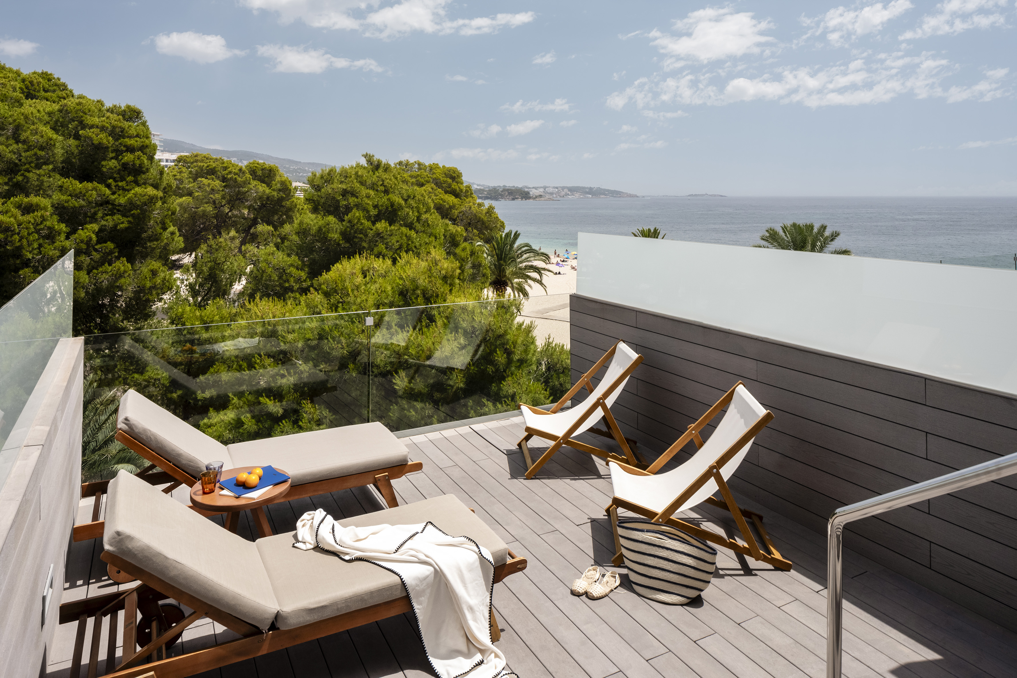 Coastal hotel balcony with sun loungers, beach, and ocean views.