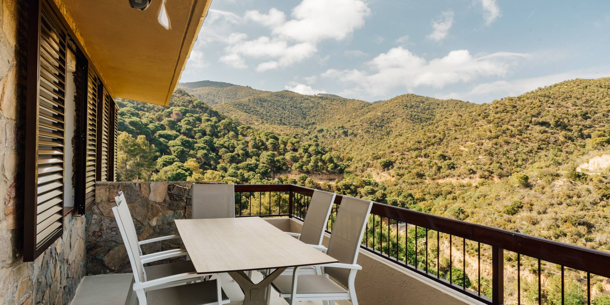 a table and chairs on a balcony overlooking a mountain