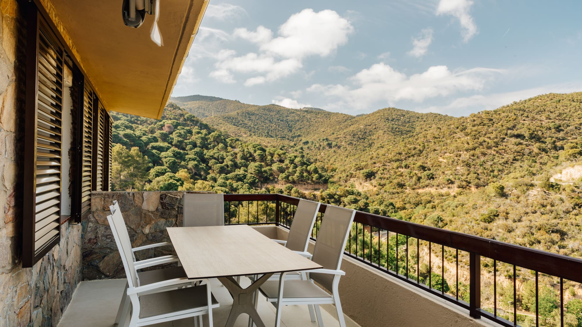 a table and chairs on a balcony overlooking a mountain