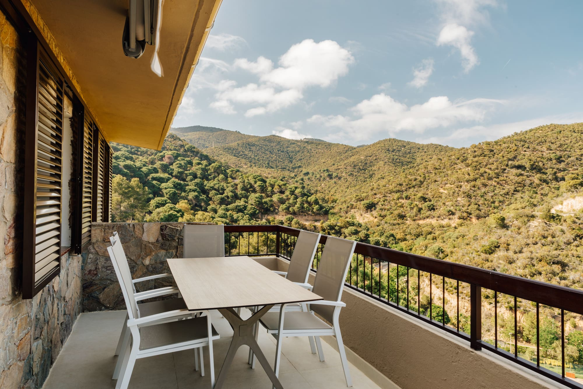 a table and chairs on a balcony overlooking a mountain