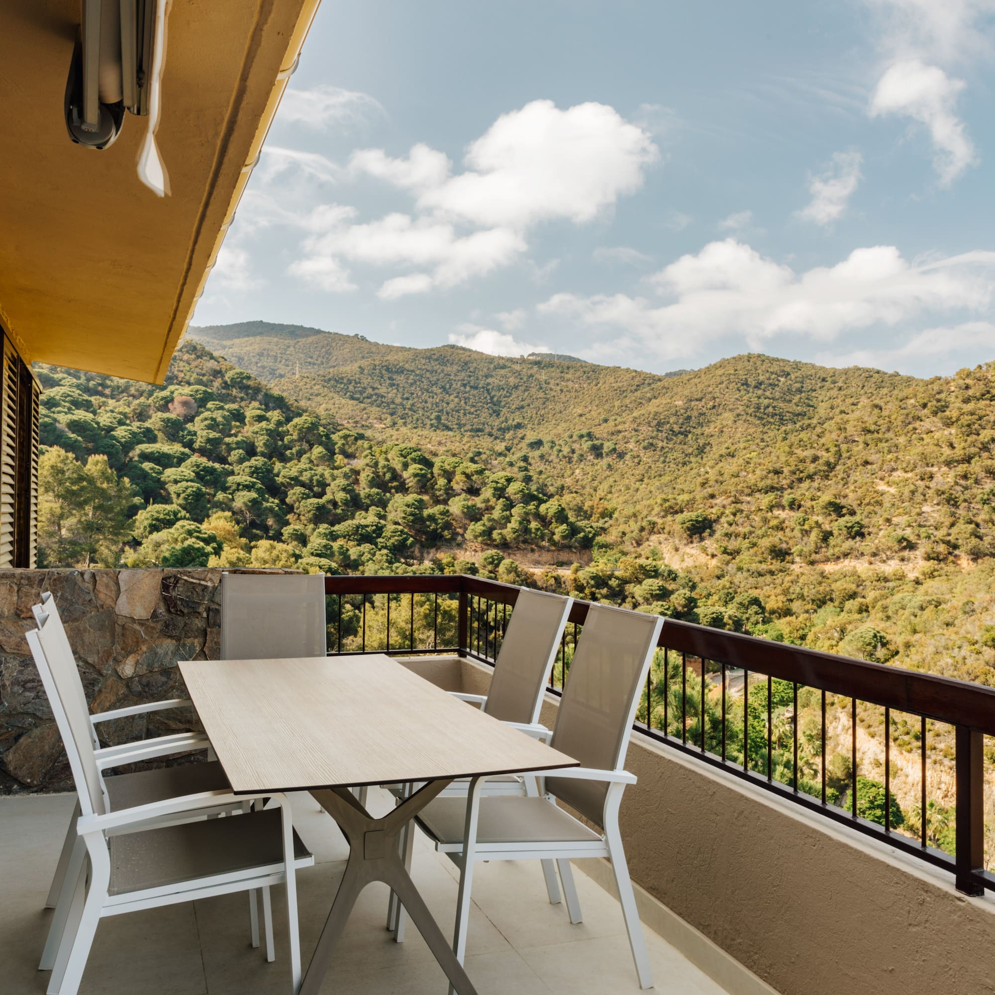 a table and chairs on a balcony overlooking a mountain