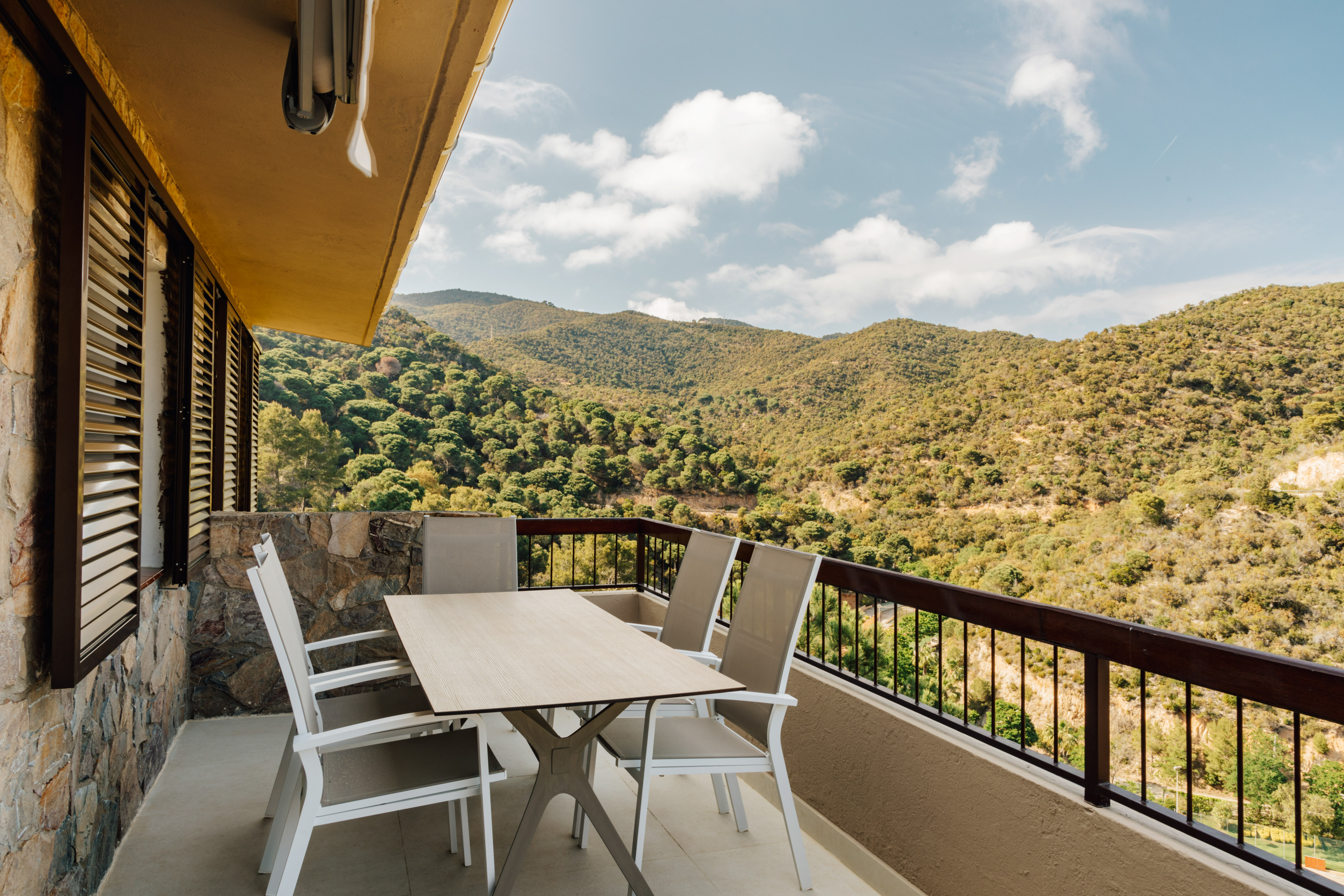 a table and chairs on a balcony overlooking a mountain