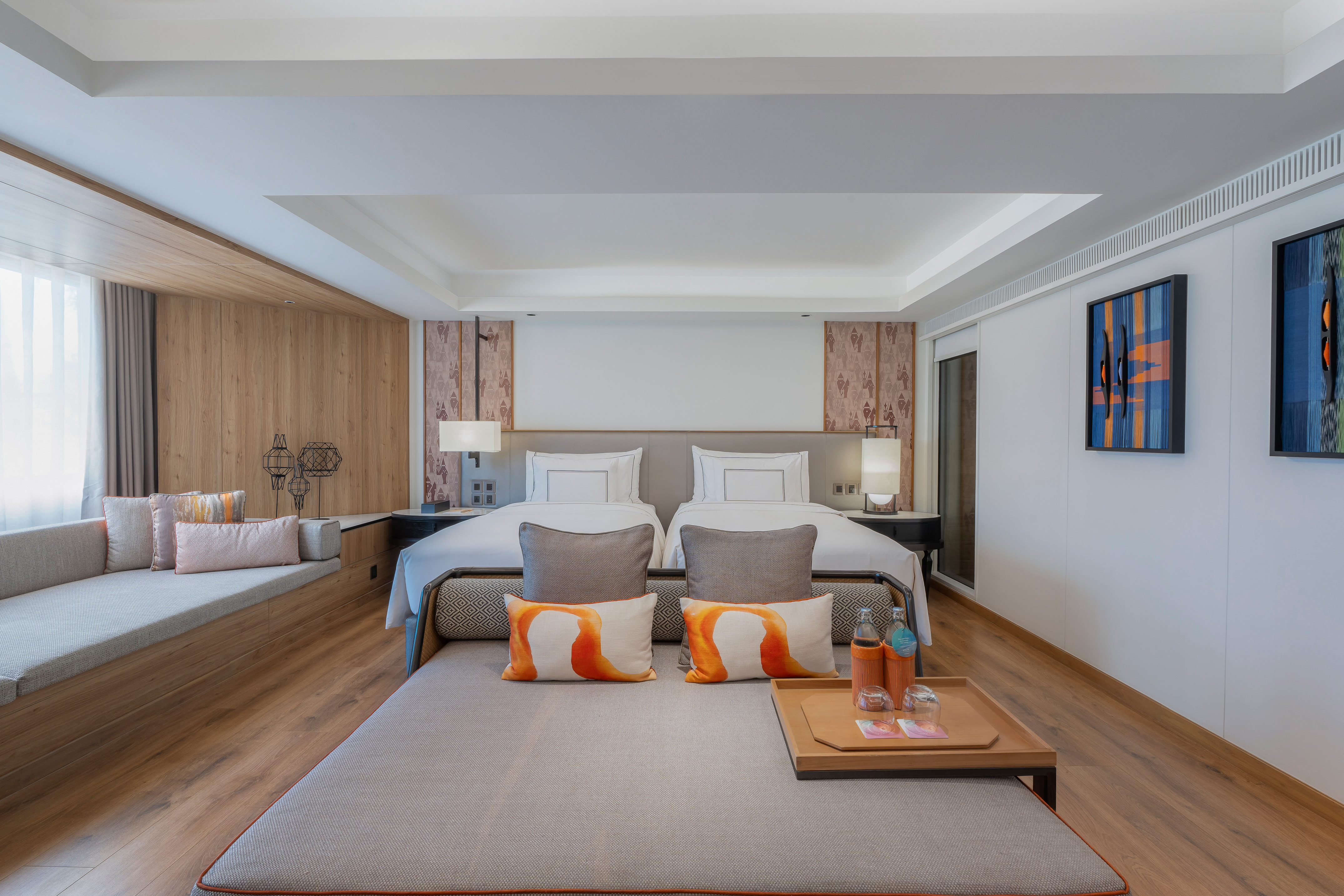Luxurious hotel bedroom with two beds, window bench, and modern decor.