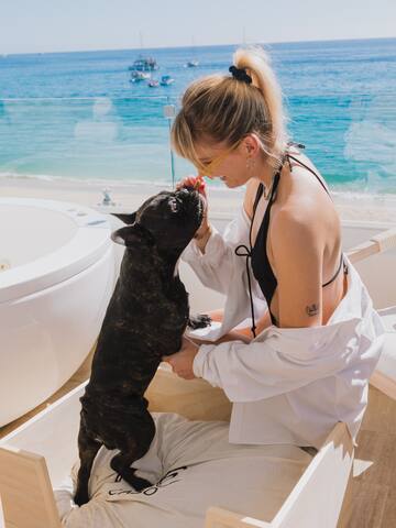 a woman in a white shirt and sunglasses petting a dog
