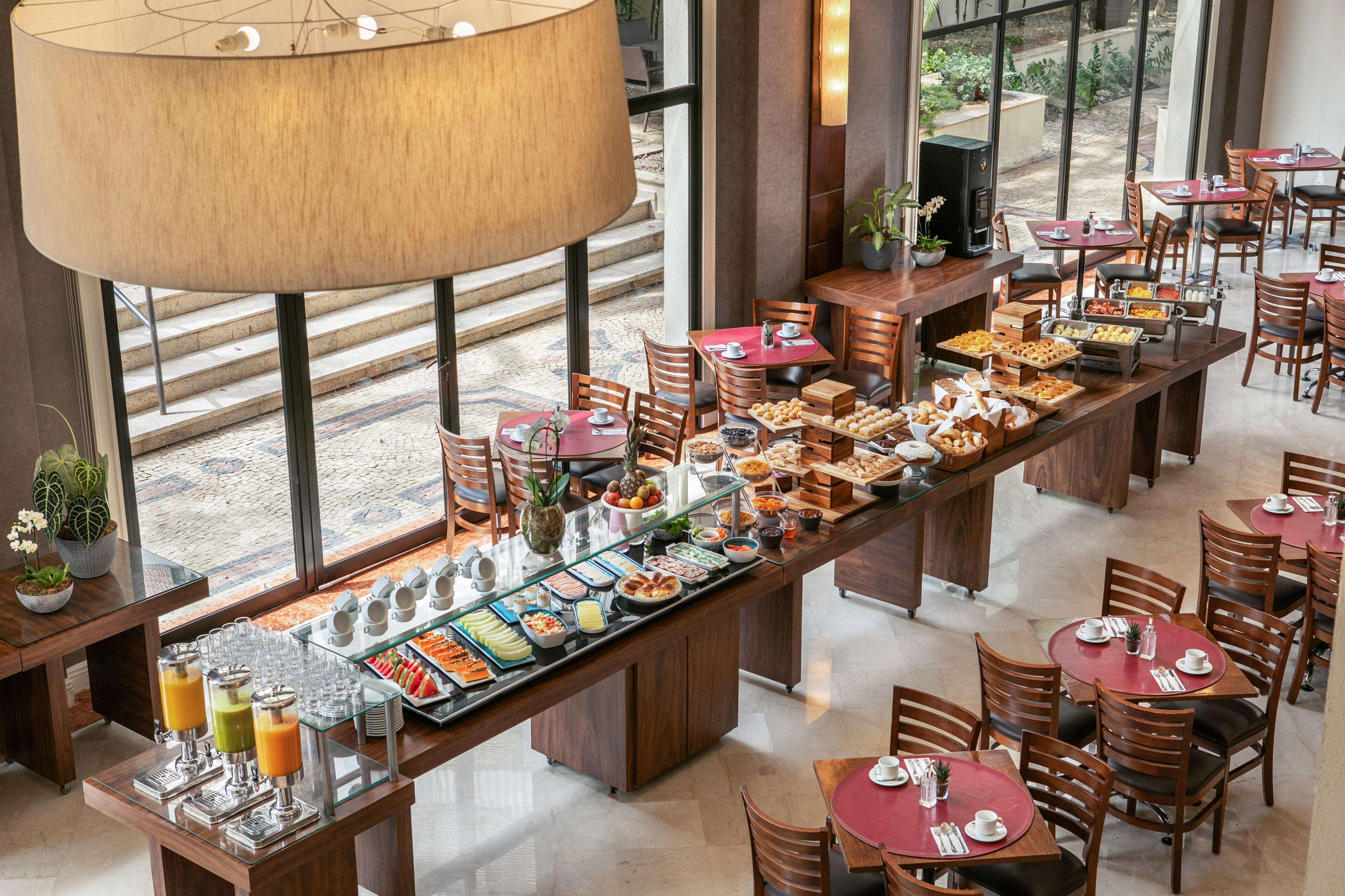 Hotel breakfast buffet with pastries, fruit, hot dishes, juices, and dining tables. - Meliá Campinas, Кампинас