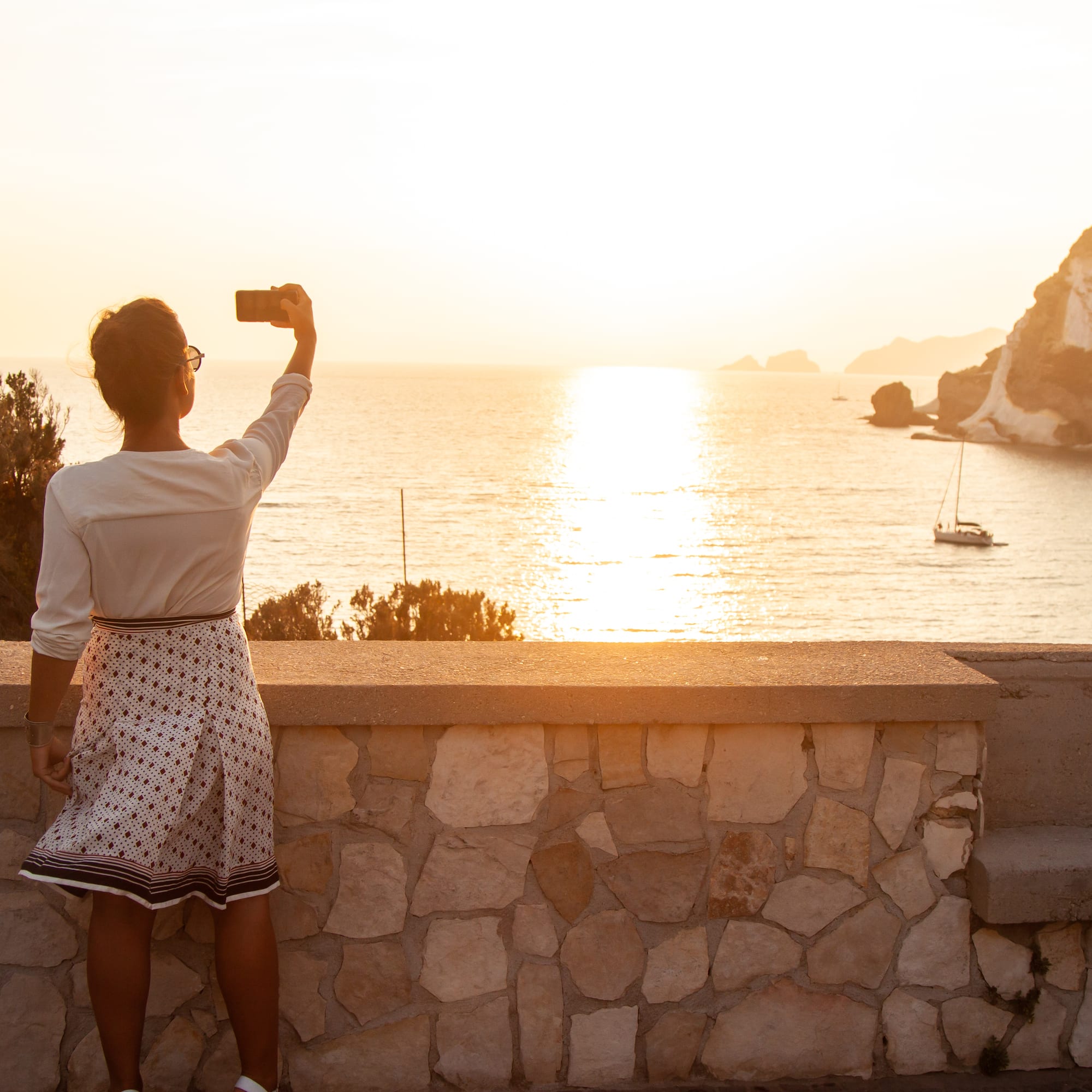 a woman taking a picture of the ocean