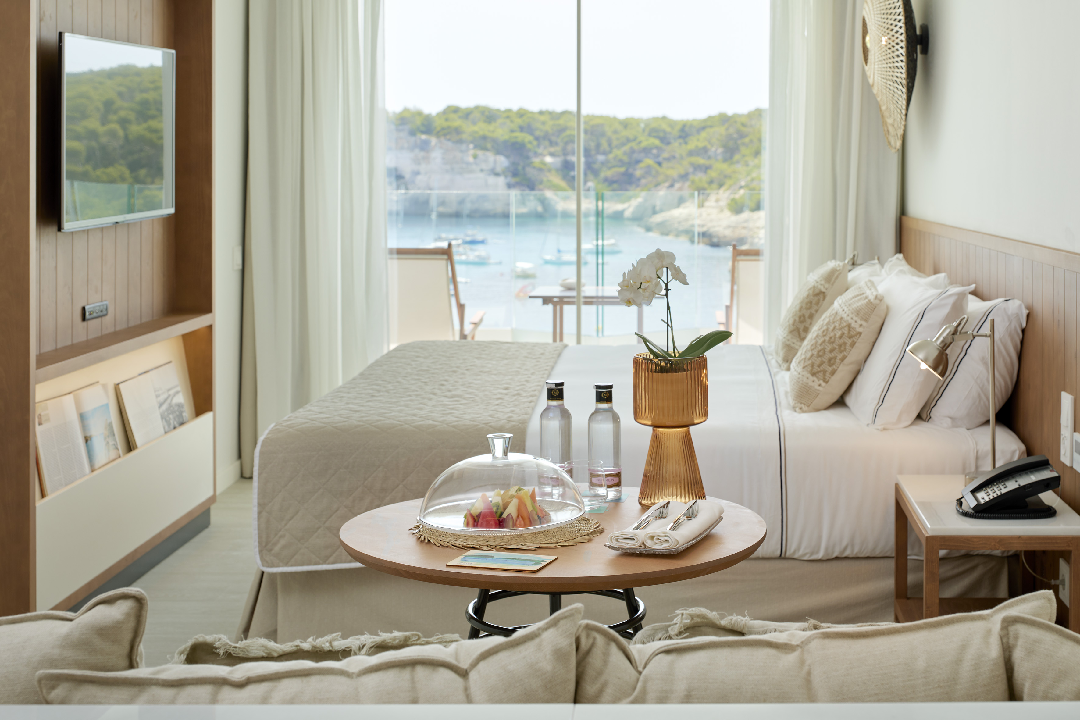 Luxury hotel room with bay view, fresh fruit platter, and modern decor.