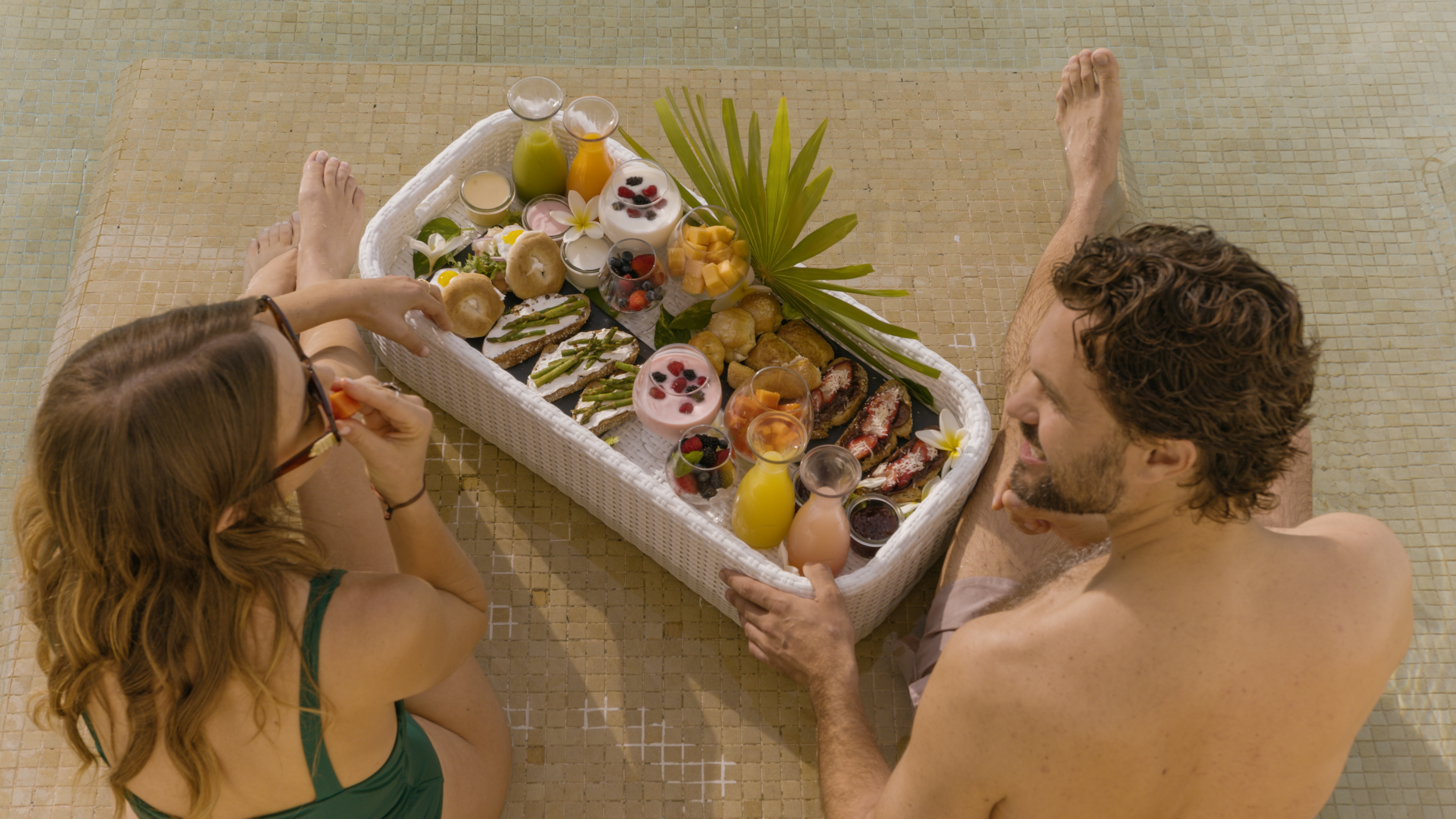 a man and woman sitting next to a basket of food