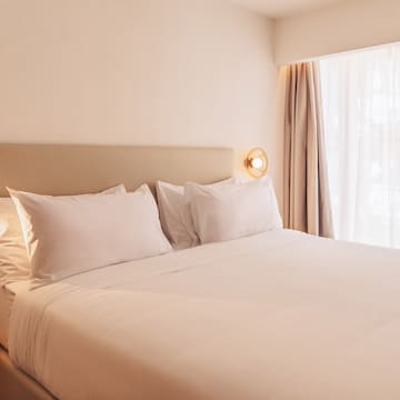 a bed with white sheets and pillows