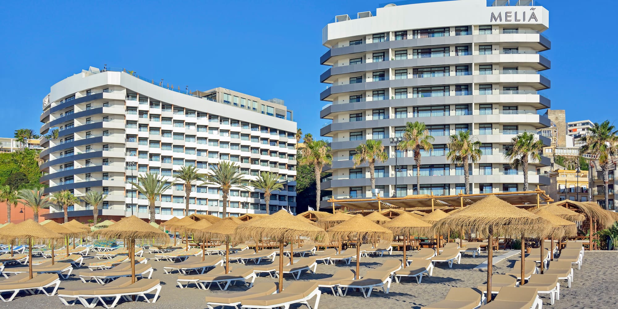 Melia beachfront hotel, sun loungers, straw umbrellas, palm trees.