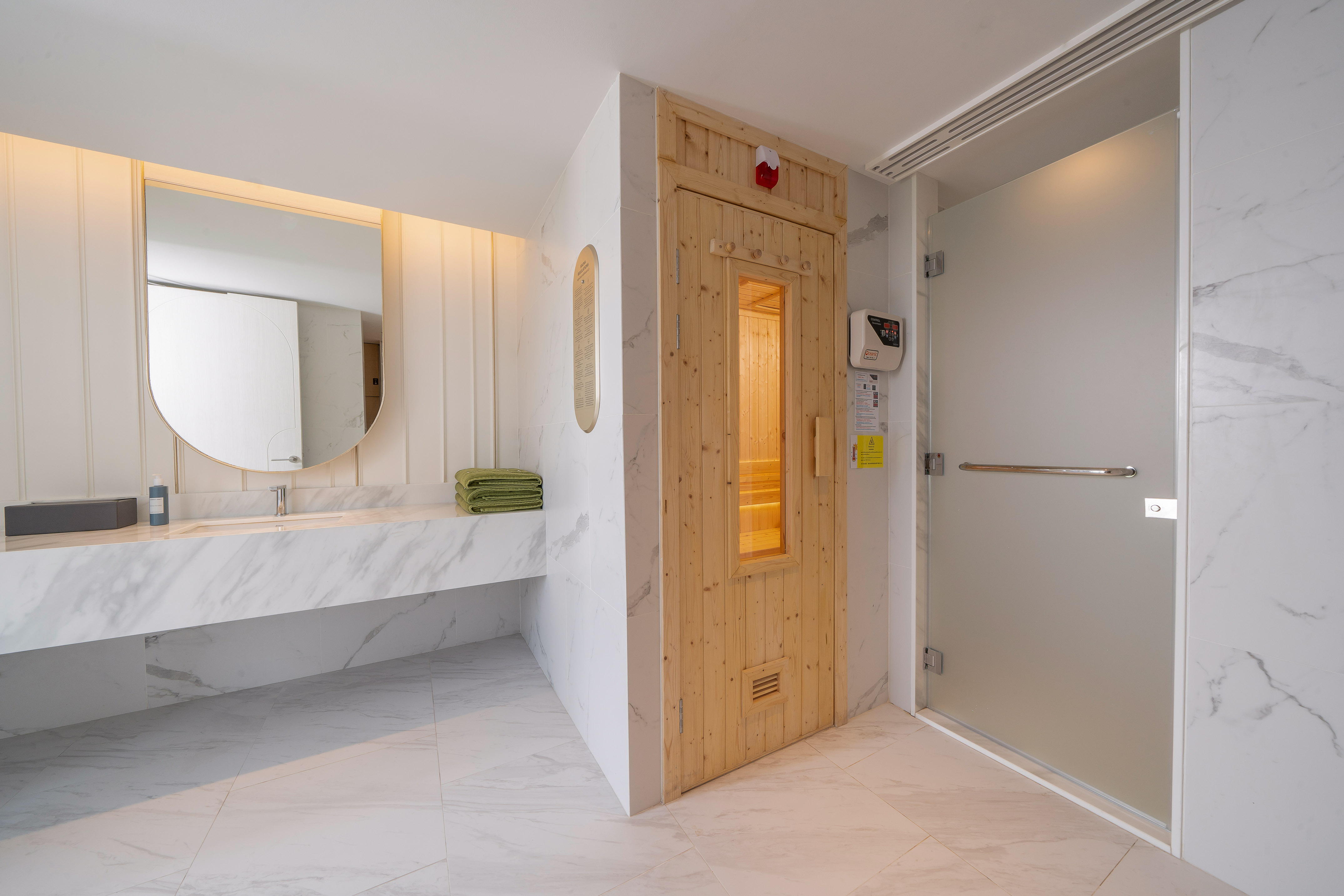 Luxury bathroom with marble vanity, wooden sauna, and frosted glass shower. - YHI Spa - Meliá Pattaya Hotel, Pattaya