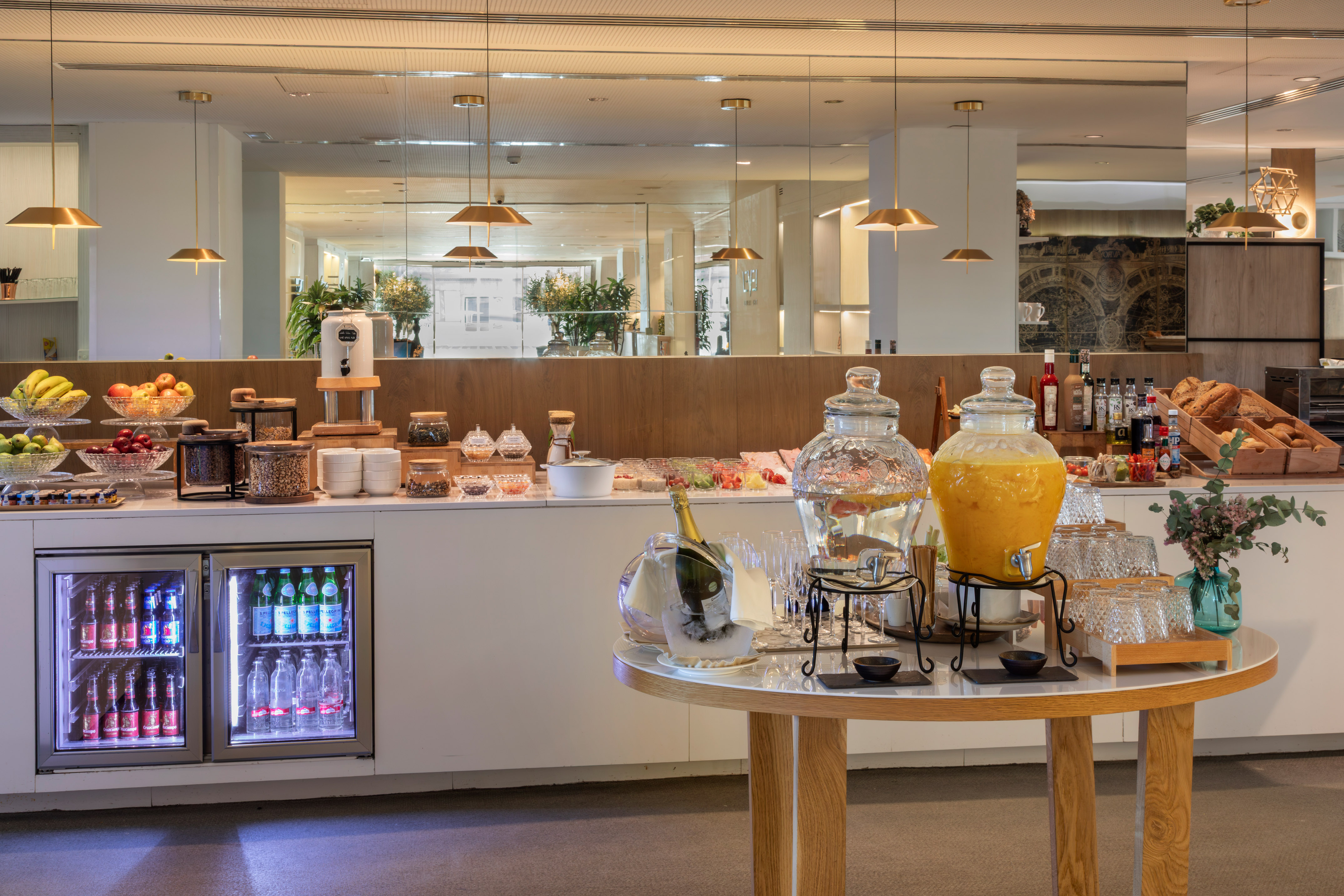 Modern breakfast buffet with fresh fruit, juices, cereals, pastries, and drinks.