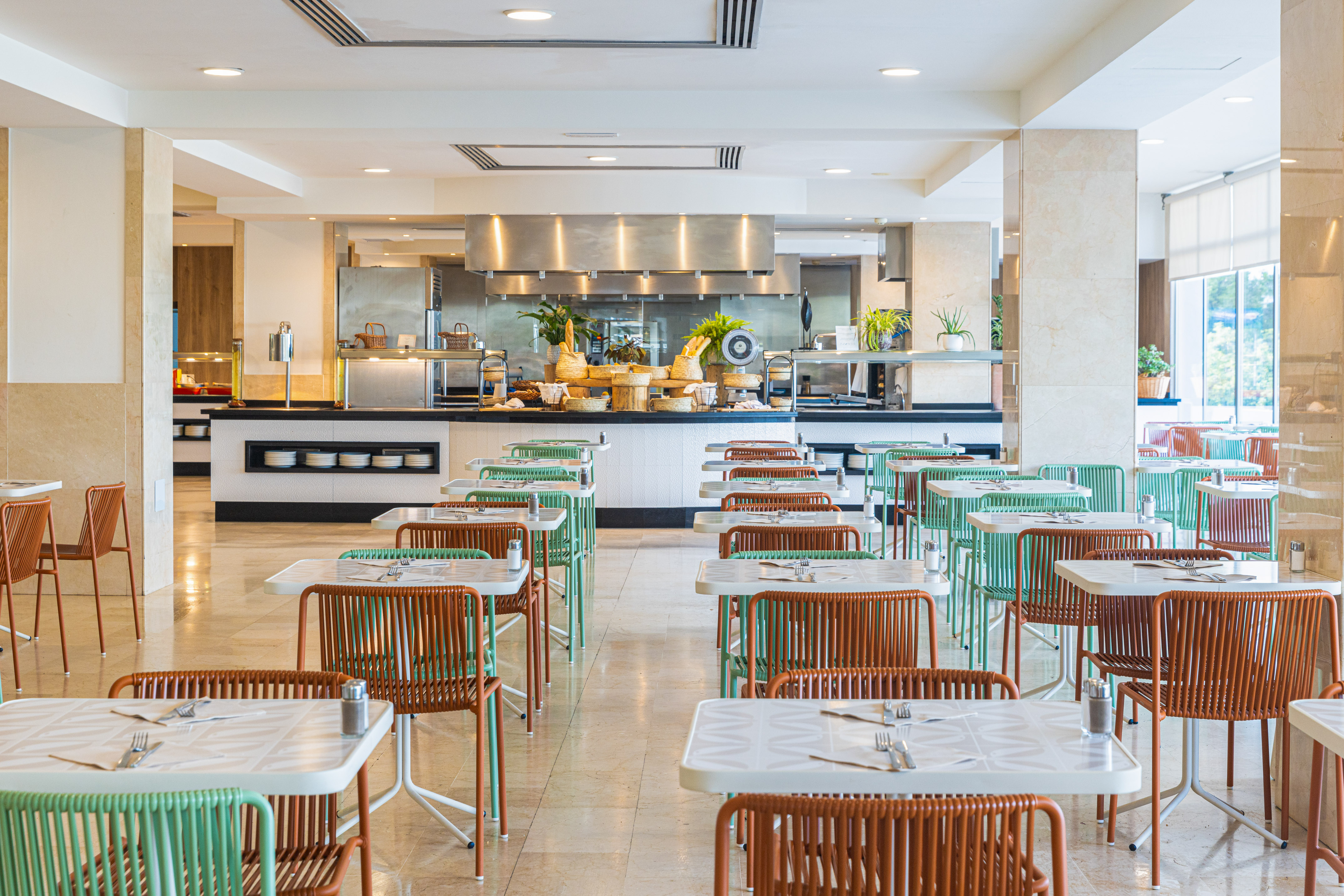 Hotel buffet dining room with colorful chairs and food serving area.