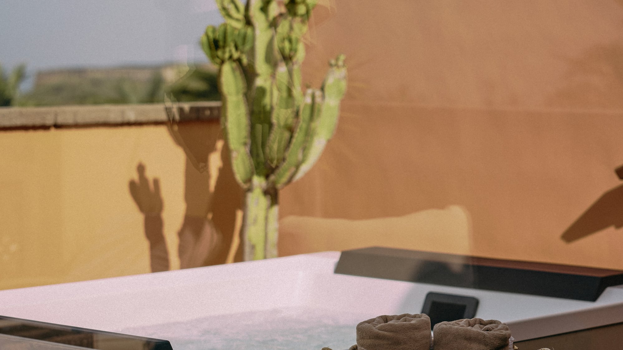 a hot tub with a basket of towels and a cactus in the background
