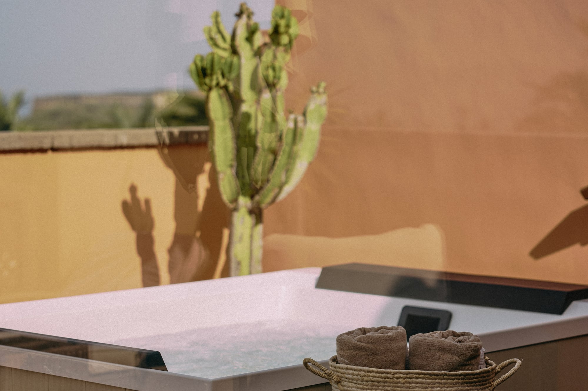 a hot tub with a basket of towels and a cactus in the background