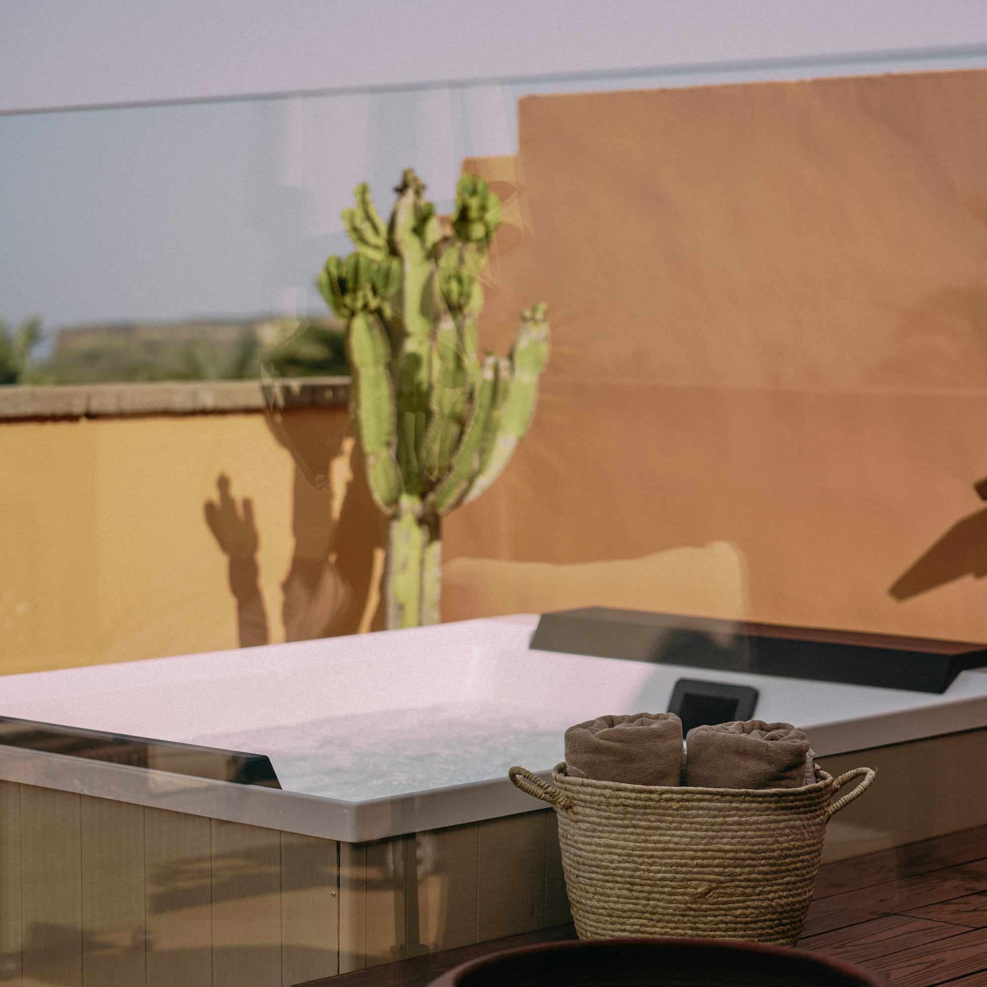 a hot tub with a basket of towels and a cactus in the background