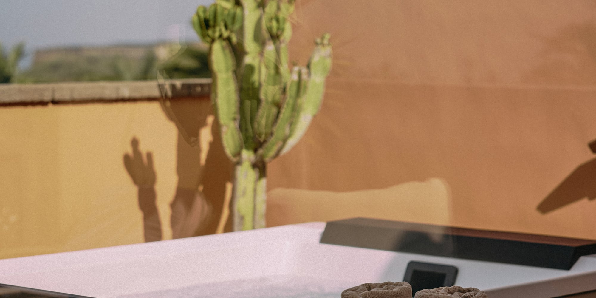 a hot tub with a basket of towels and a cactus in the background