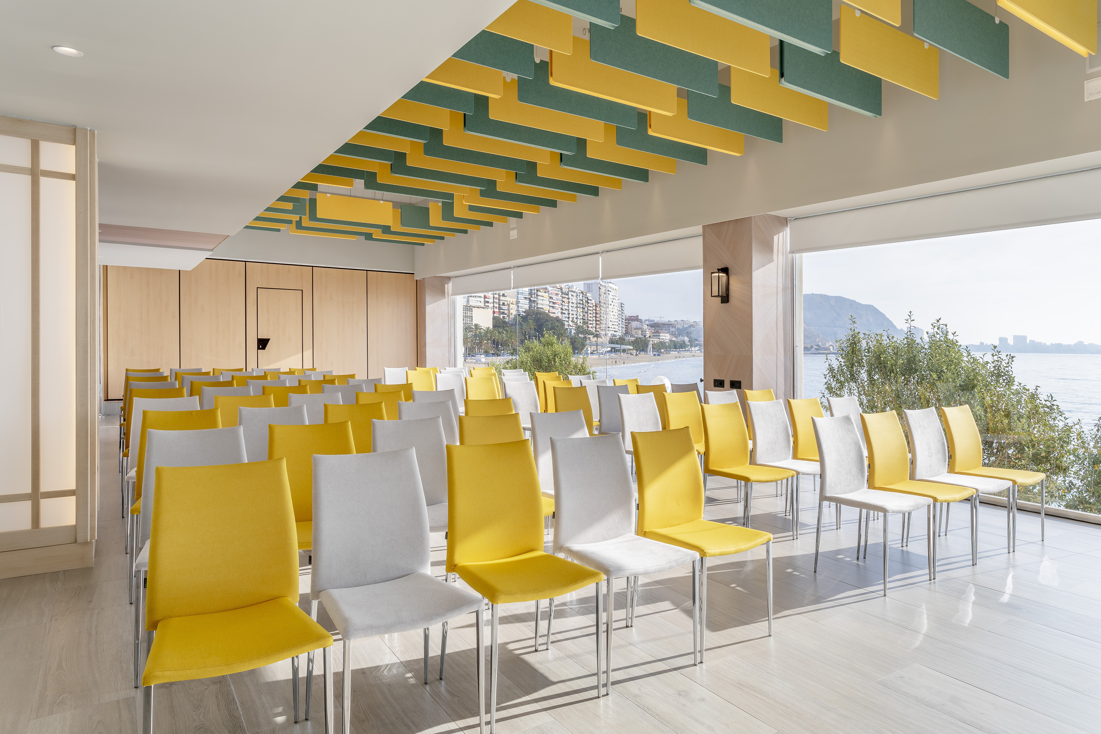 Conference room with yellow & white chairs, acoustic ceiling, ocean view.