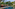 Outdoor resort pool with lounge chairs, orange sofas, umbrellas, and tropical trees.